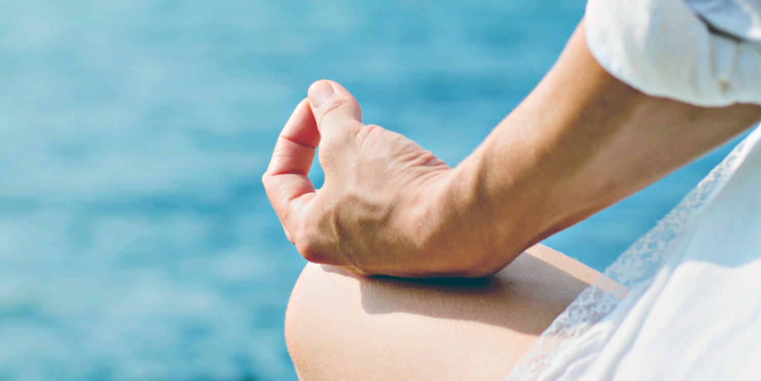 A man meditating by a body of water - Soulshine's Health and Wellness Section
