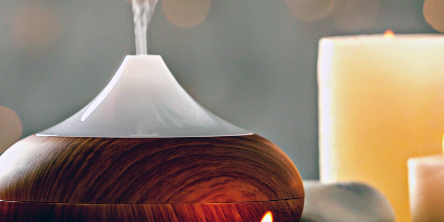 Diffuser releasing steam to the room with candles in the background  -  Soulshine's Diffuser and Oils Section